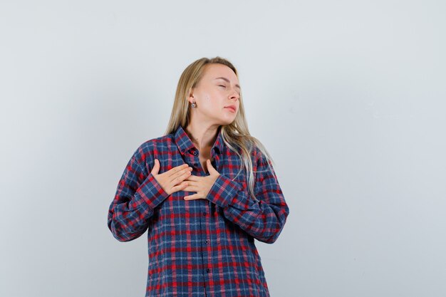 Free photo blonde lady in casual shirt holding hands on chest , front view.