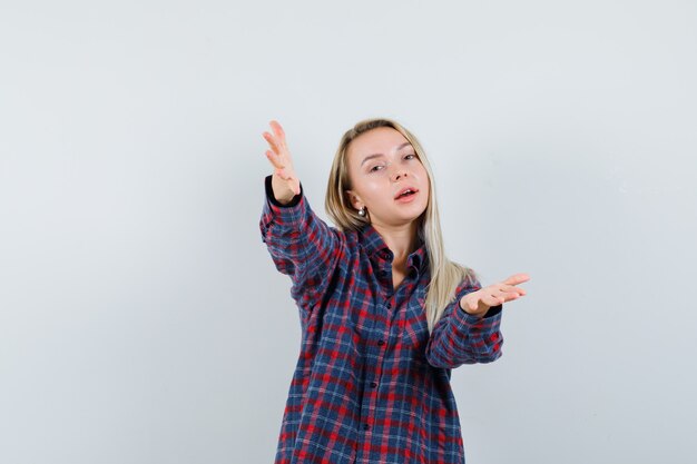 Blonde lady in casual shirt opening arms for hug and looking cute , front view.