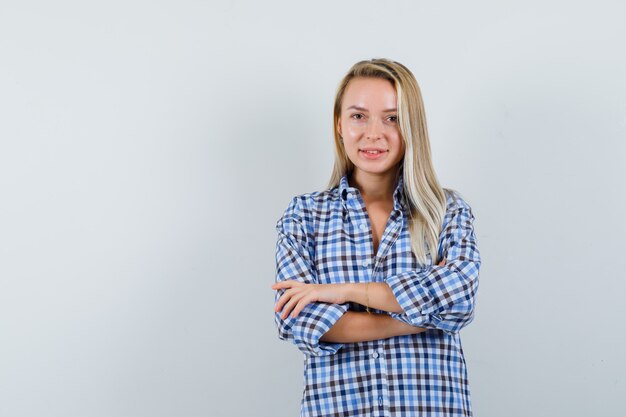 Signora bionda in camicia casual in piedi con le braccia incrociate e guardando fiducioso