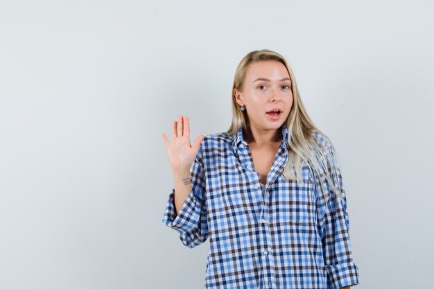 Blonde lady in casual shirt waving hand and looking cheery