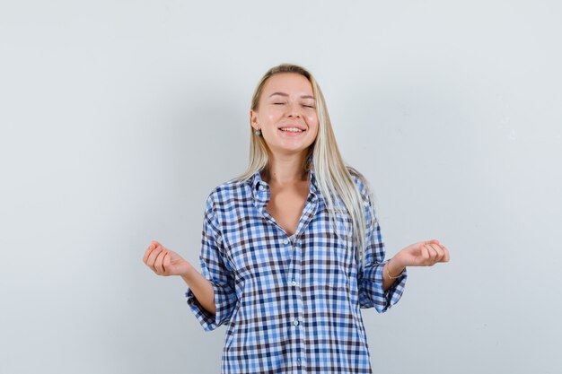 Blonde lady doing meditation with closed eyes in checked shirt and looking lucky