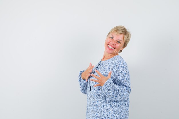 Blonde lady expressing herself in blouse and looking merry , front view. space for text