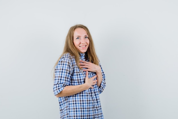 Blonde lady holding hands on chest in shirt and looking ashamed.