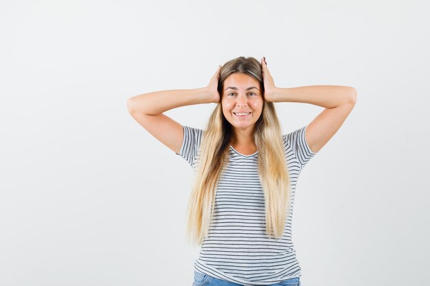 Blonde lady holding hands on her head in t-shirt front view.