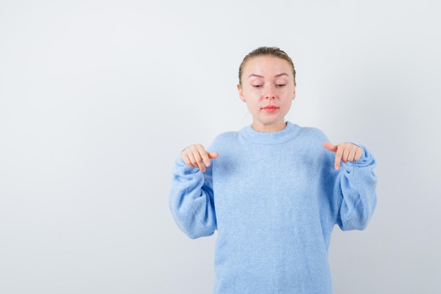 ブロンドの女性は白い背景の下に何かを示しています