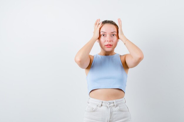 금발의 여자는 흰색 배경에 충격을 받은 감정을 보이고 있다