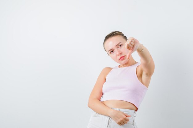 Blonde lady is showing unfavorable sign on white background