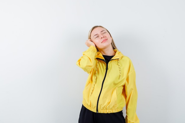 Blonde lady leaning head on hand in tracksuit and looking dreamy , front view.