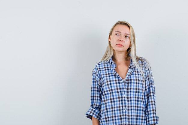 Blonde lady looking away in checked shirt and looking thoughtful