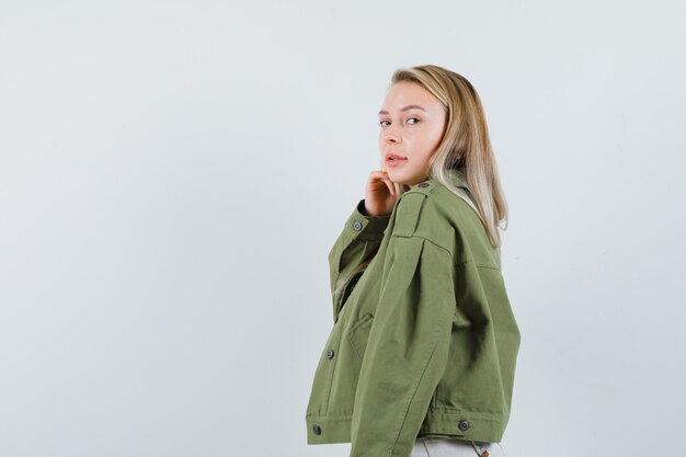 Blonde lady looking at camera in jacket, pants and looking alluring .