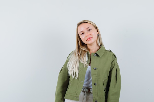 Blonde lady looking at camera in jacket, pants and looking cheerful , front view.