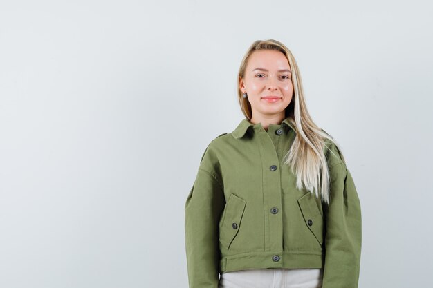 Blonde lady looking at camera in jacket, pants and looking pretty , front view.