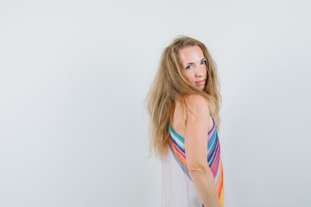 Free photo blonde lady looking over her shoulder in summer dress and looking charming .