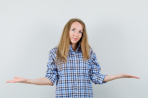 Free photo blonde lady making scales gesture in shirt and looking cheerful.