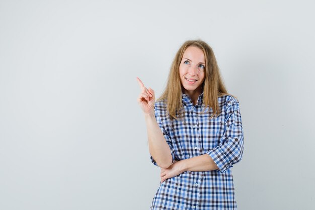 blonde lady pointing up in shirt and looking hopeful.