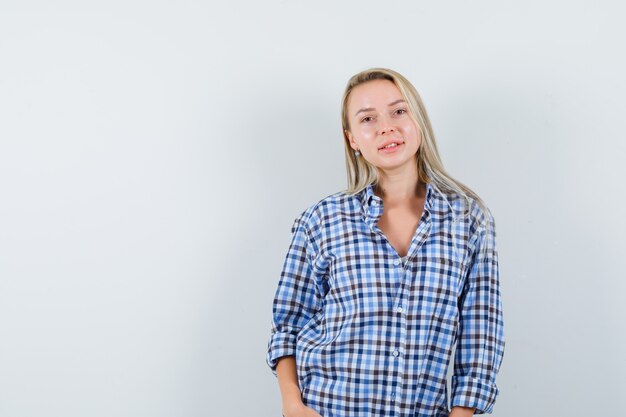 Blonde lady posing while standing in checked shirt and looking confident