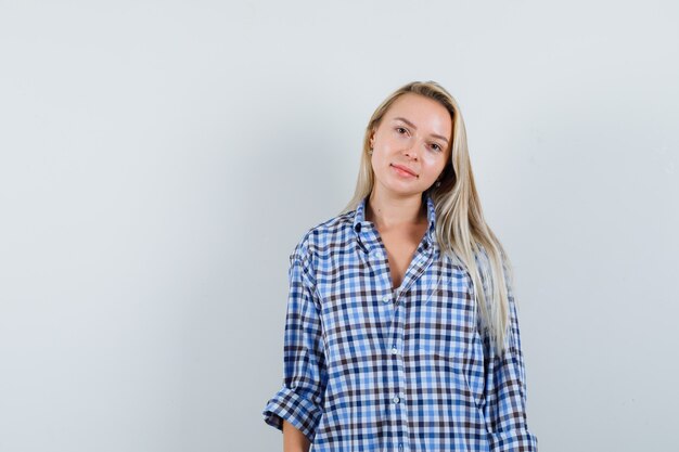 Blonde lady posing while standing in checked shirt and looking sensible