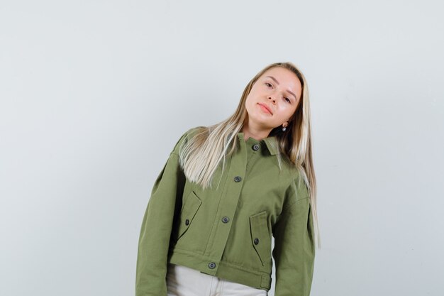 Blonde lady posing while standing in jacket, pants and looking charming. front view.