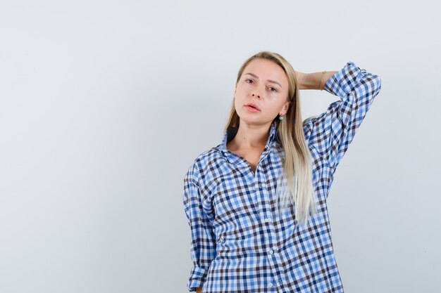 Blonde lady posing with hand behind head in checked shirt and looking nice