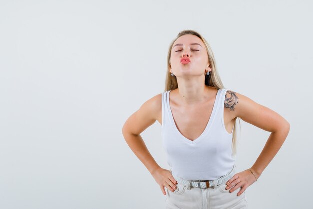 Blonde lady pouting lips in singlet, pants and looking lovely , front view.