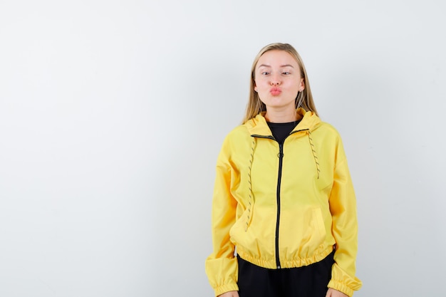 Free photo blonde lady pouting lips, squinting eyes in tracksuit and looking funny , front view.