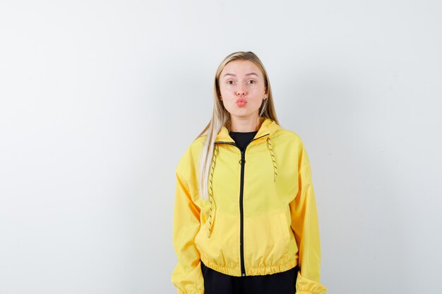 Blonde lady pouting lips in tracksuit and looking cute , front view.