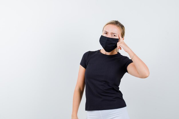 Blonde lady pressing finger on temples in black t-shirt isolated