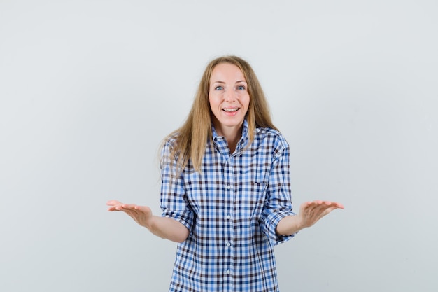 Blonde lady pretending to hold or show something in shirt and looking cheerful ,