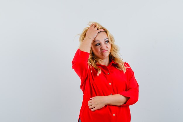 Blonde lady in red shirt adjusting her hair space for text