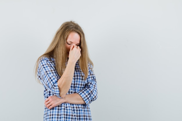 Free photo blonde lady rubbing eyes and nose in shirt and looking tired.