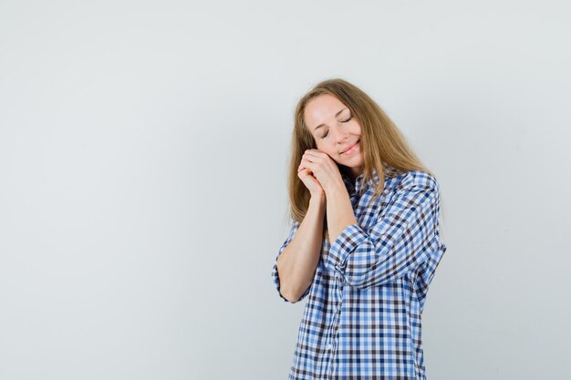 Blonde lady in shirt leaning cheek on clasped hands and looking peaceful ,