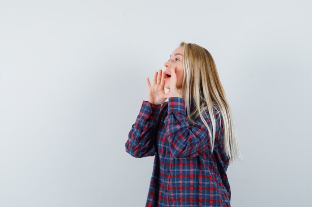 Blonde lady shouting or announcing something in casual shirt , front view.