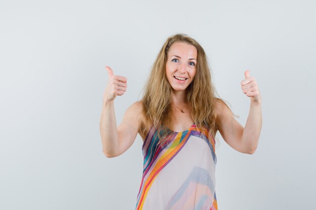 Blonde lady showing double thumbs up in summer dress and looking merry 