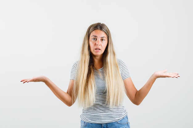 Free photo blonde lady showing helpless gesture in t-shirt and looking puzzled , front view.