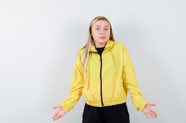 Free photo blonde lady showing helpless gesture in tracksuit and looking confused. front view.