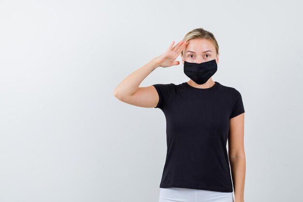 Blonde lady showing salute gesture in black t-shirt isolated