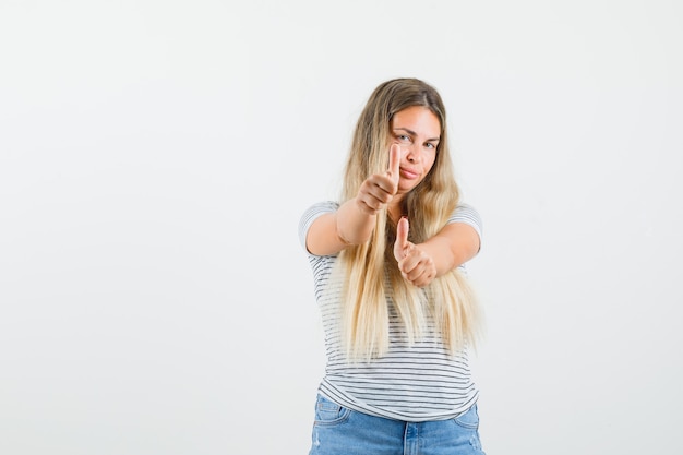 Blonde lady showing thumb up in t-shirt and looking ready , front view.