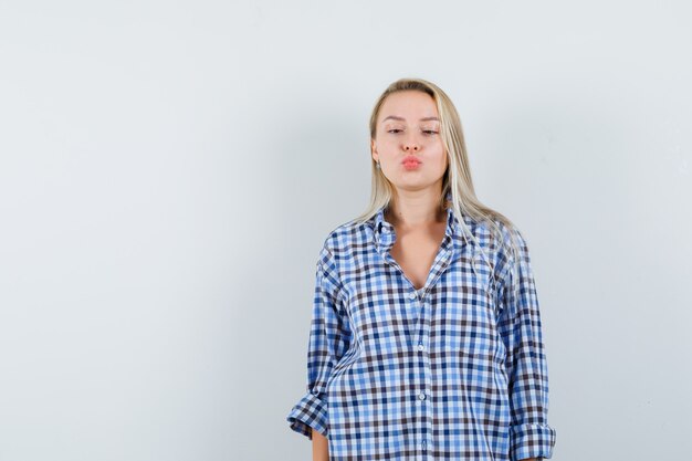 Blonde lady squinting eyes, pouting lips in checked shirt