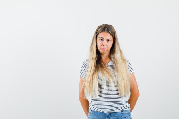 Blonde lady standing in t-shirt and looking upset. front view.