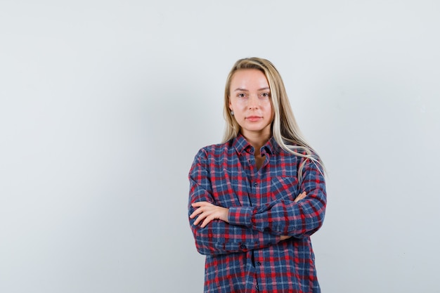 Blonde lady standing with crossed arms in casual shirt and looking confident. front view.