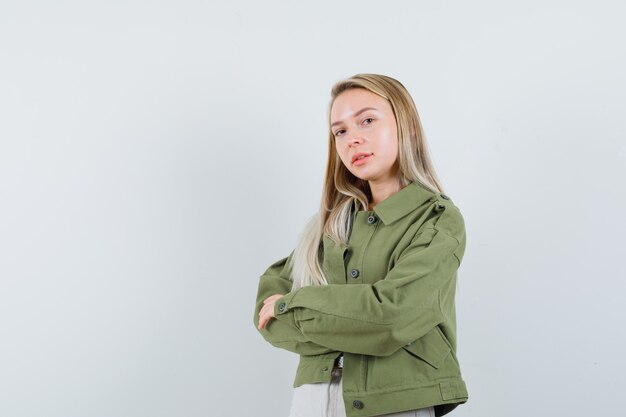 Blonde lady standing with crossed arms in jacket, pants and looking confident. front view.