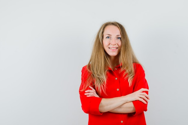 Blonde lady standing with crossed arms in red shirt and looking jolly ,