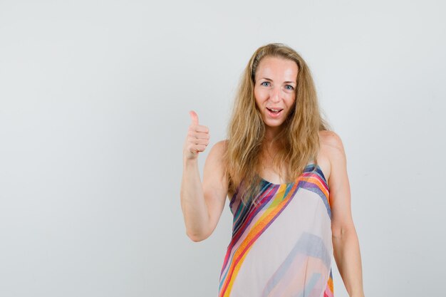 Blonde lady in summer dress showing thumb up and looking cheerful 