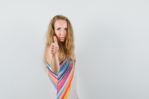 Free photo blonde lady in summer dress showing thumb up and looking cheerful .