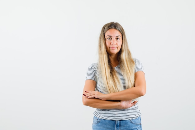 Free photo blonde lady in t-shirt standing with crossed arms and looking self-satisfied , front view.