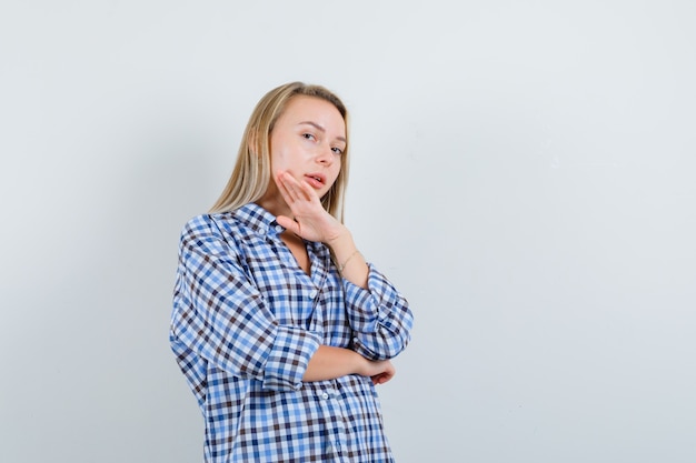 Blonde lady touching her chin in casual shirt and looking glamorous