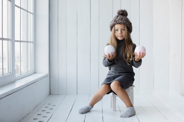 Free photo blonde little girl offering snowballs