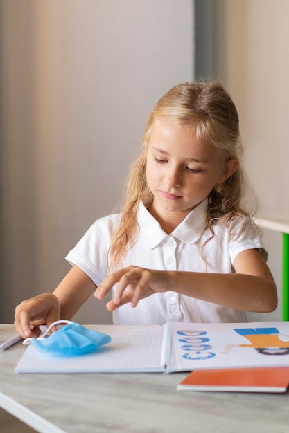 Blonde little girl wanting to take her face mask