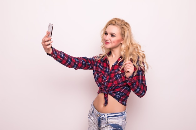 Selfieを作る短い赤いtシャツで金髪の長い髪の少女