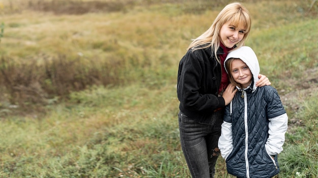 Free photo blonde mother and little girl posing in nature